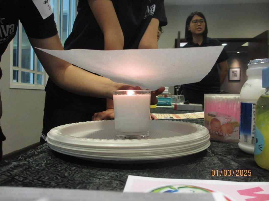 A lit candle on a stack of paper plates during a STEM x Magic experiment